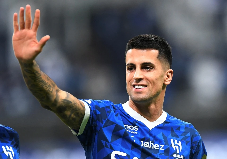 João Cancelo vẫy tay trong trang phục thi đấu màu xanh.